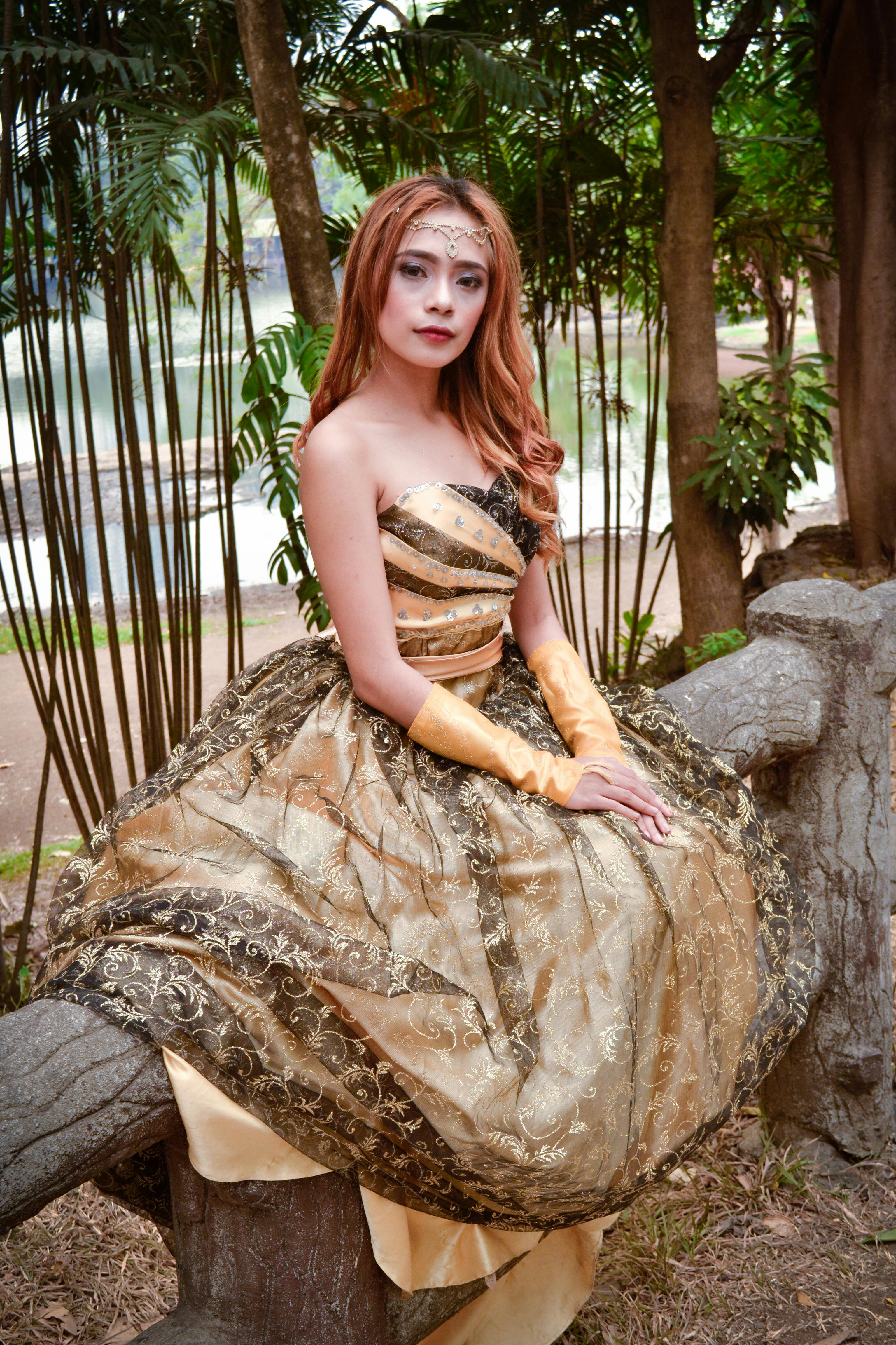 一位身着优雅金色连衣裙的女子在户外摆着姿势，散发着魅力与风格