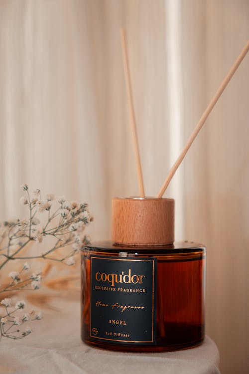 A reed diffuser with a wooden stick and flowers