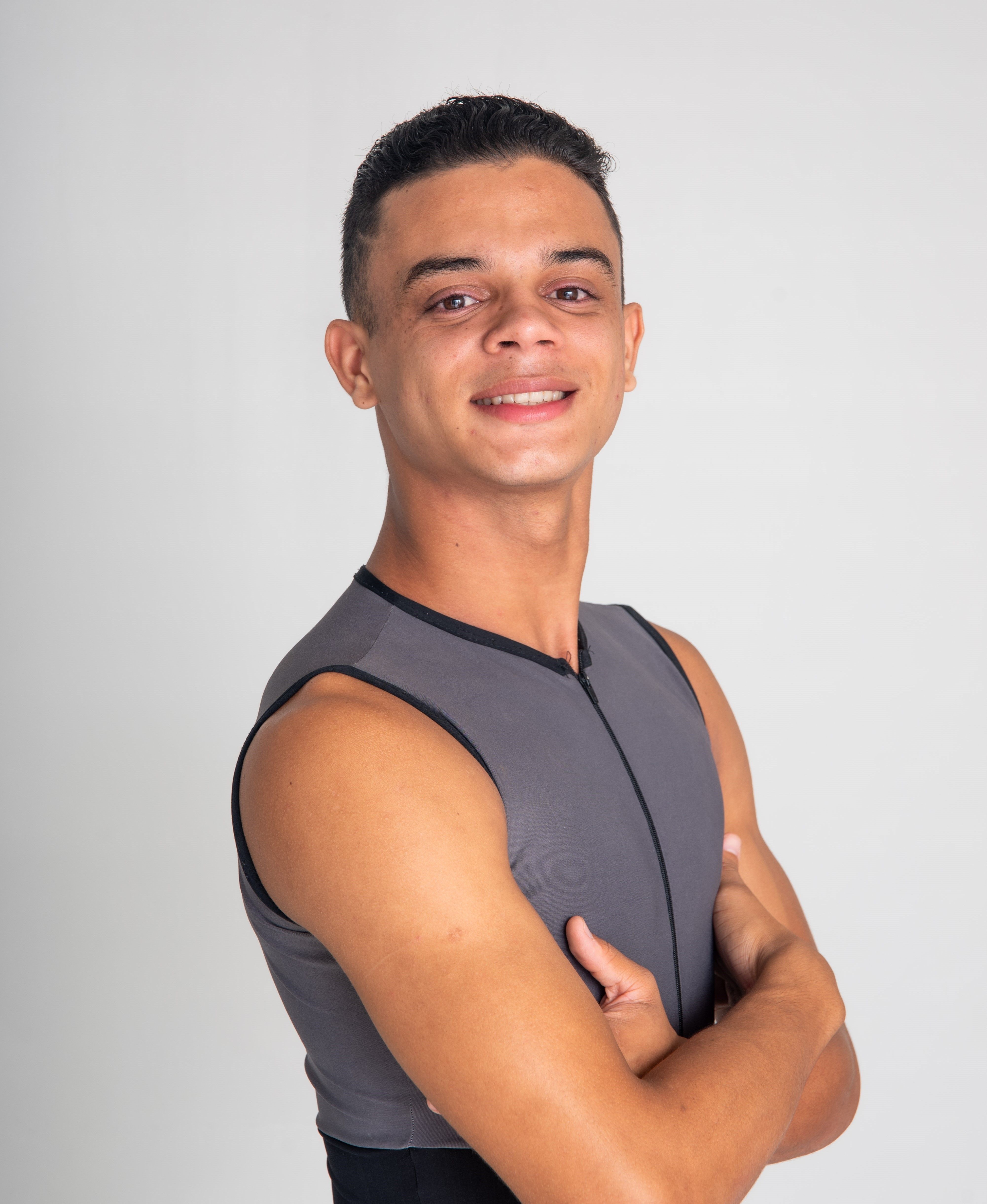 Portrait of a confident young man with arms crossed, smiling in a studio setting.