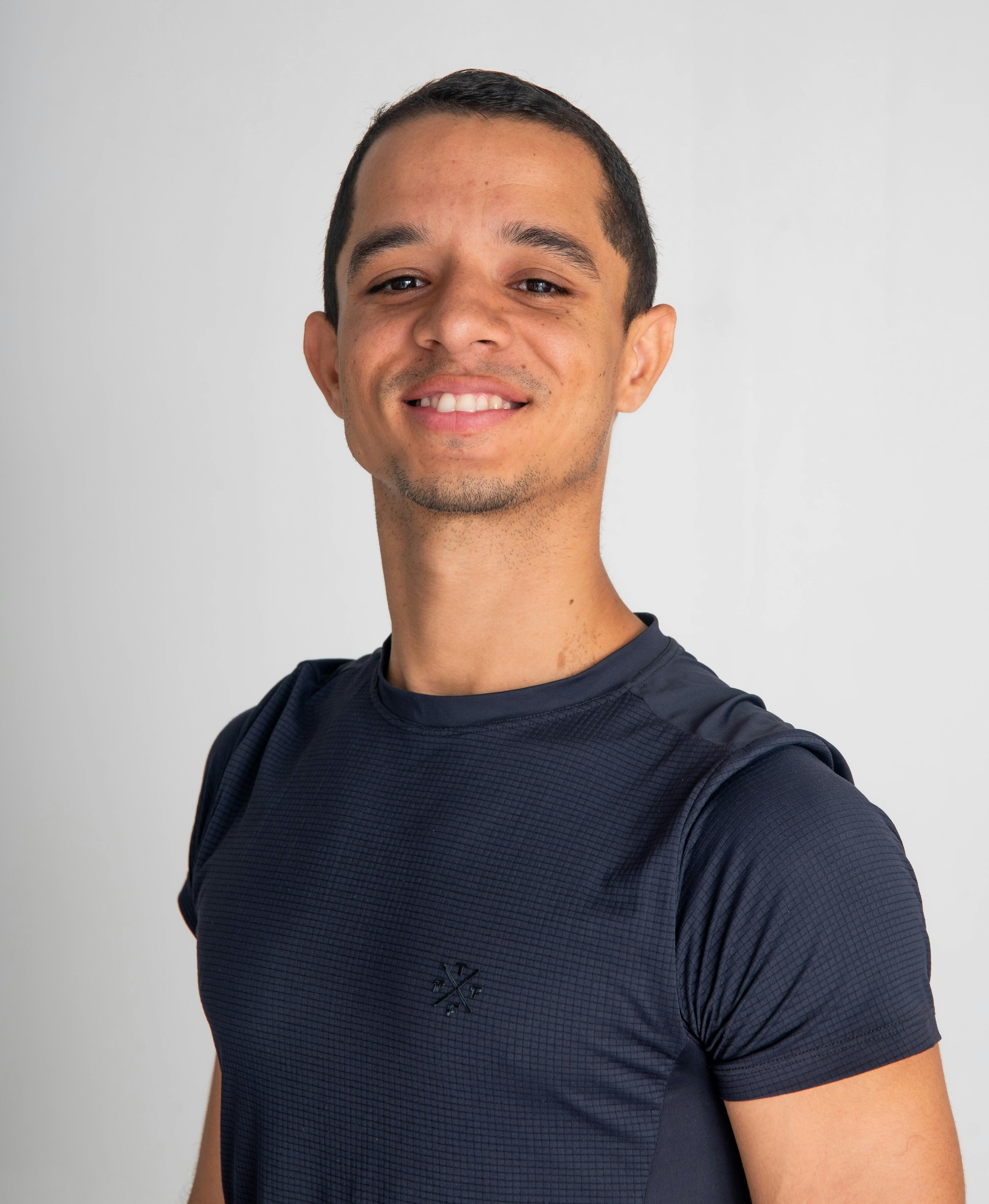 Portrait of a smiling man in a navy T-shirt against a white background.