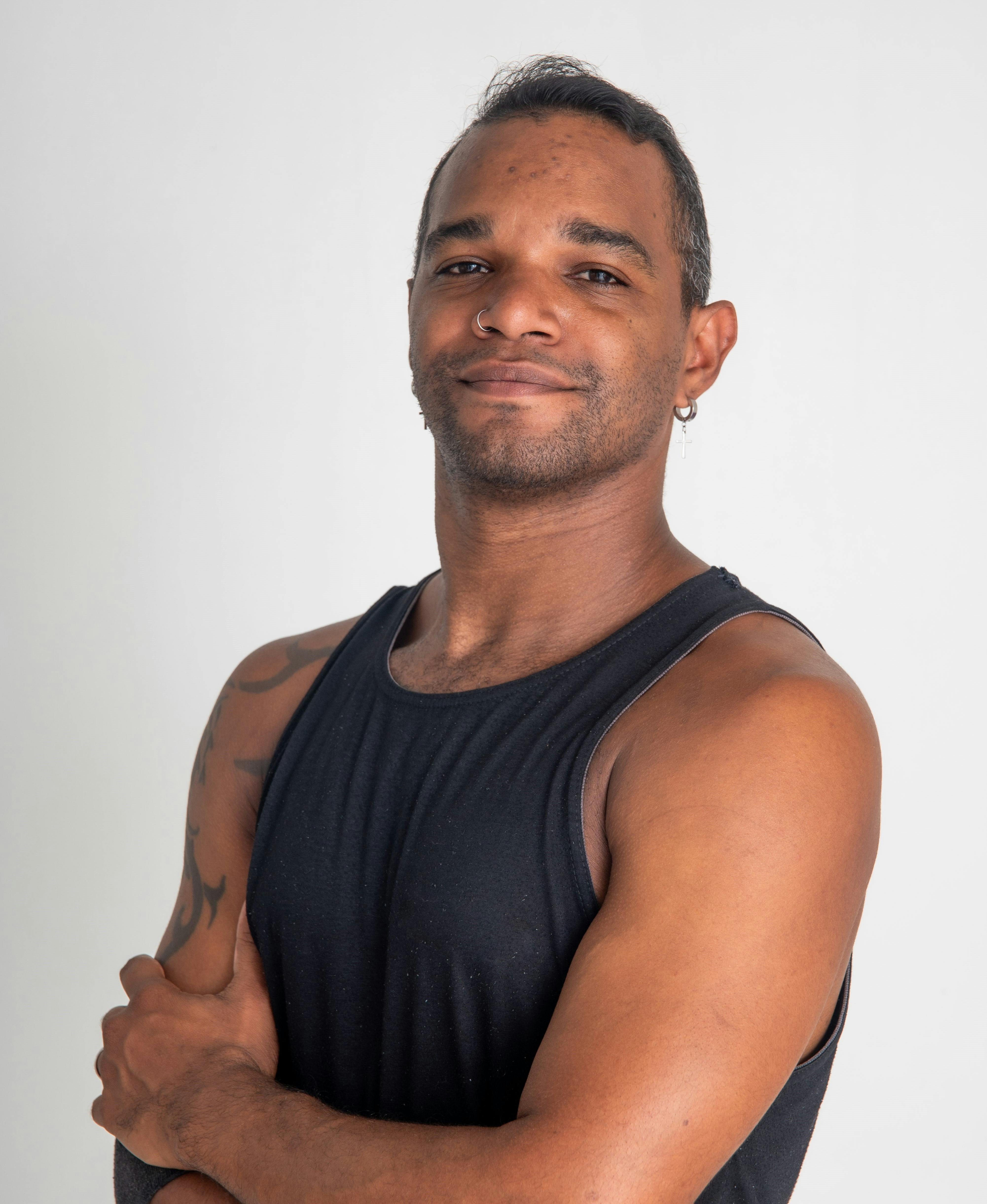 Portrait of a muscular man confidently posing with arms crossed in a studio setting.