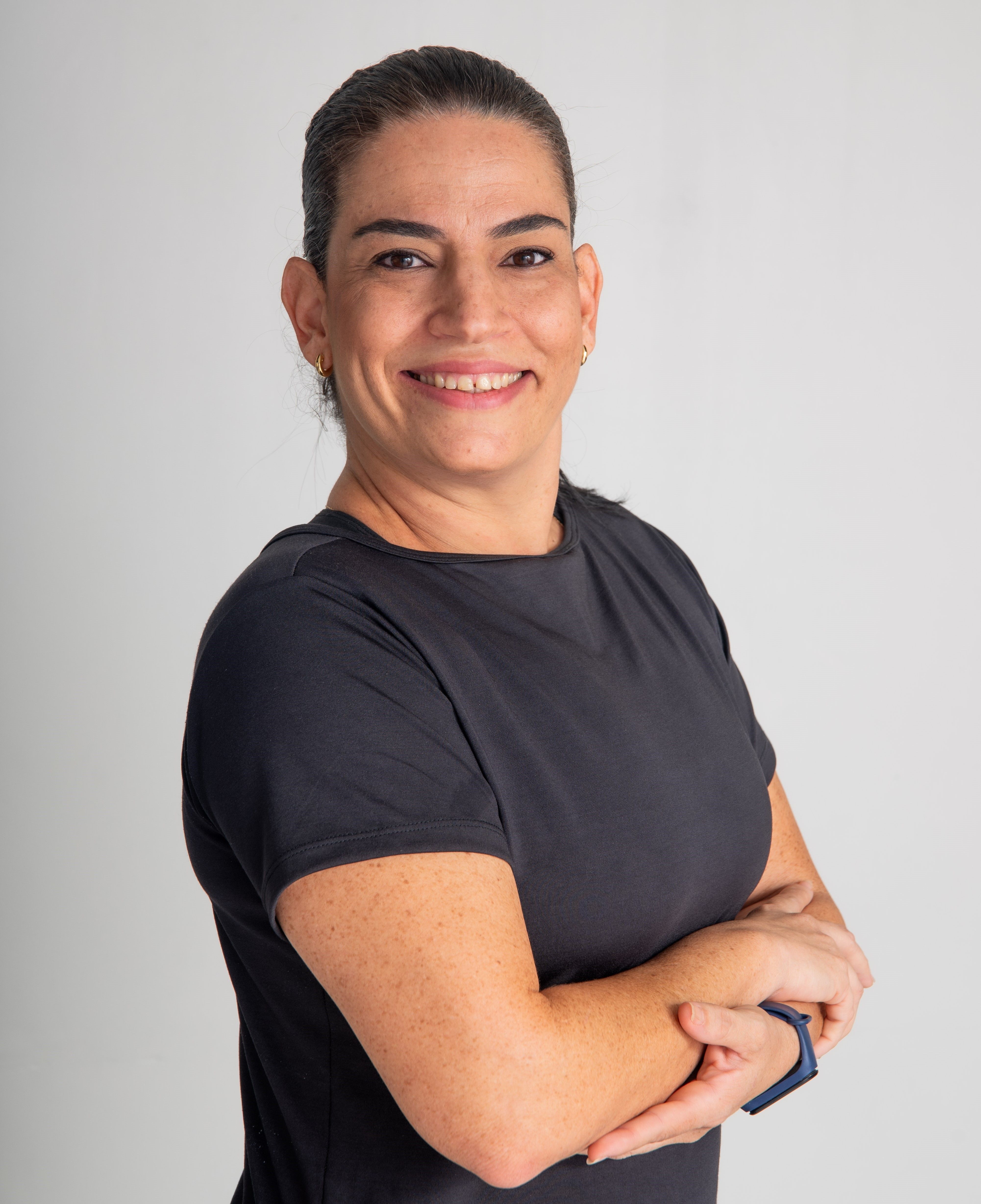 Portrait of a woman in a black t-shirt, smiling confidently against a white background.