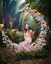 一位身着花裙的女子在五彩缤纷的鲜花和郁郁葱葱的绿植间摆好姿势，营造出梦幻般的场景