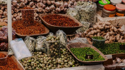 Vibrant display of fresh vegetables, spices, and herbs at a bustling outdoor market.