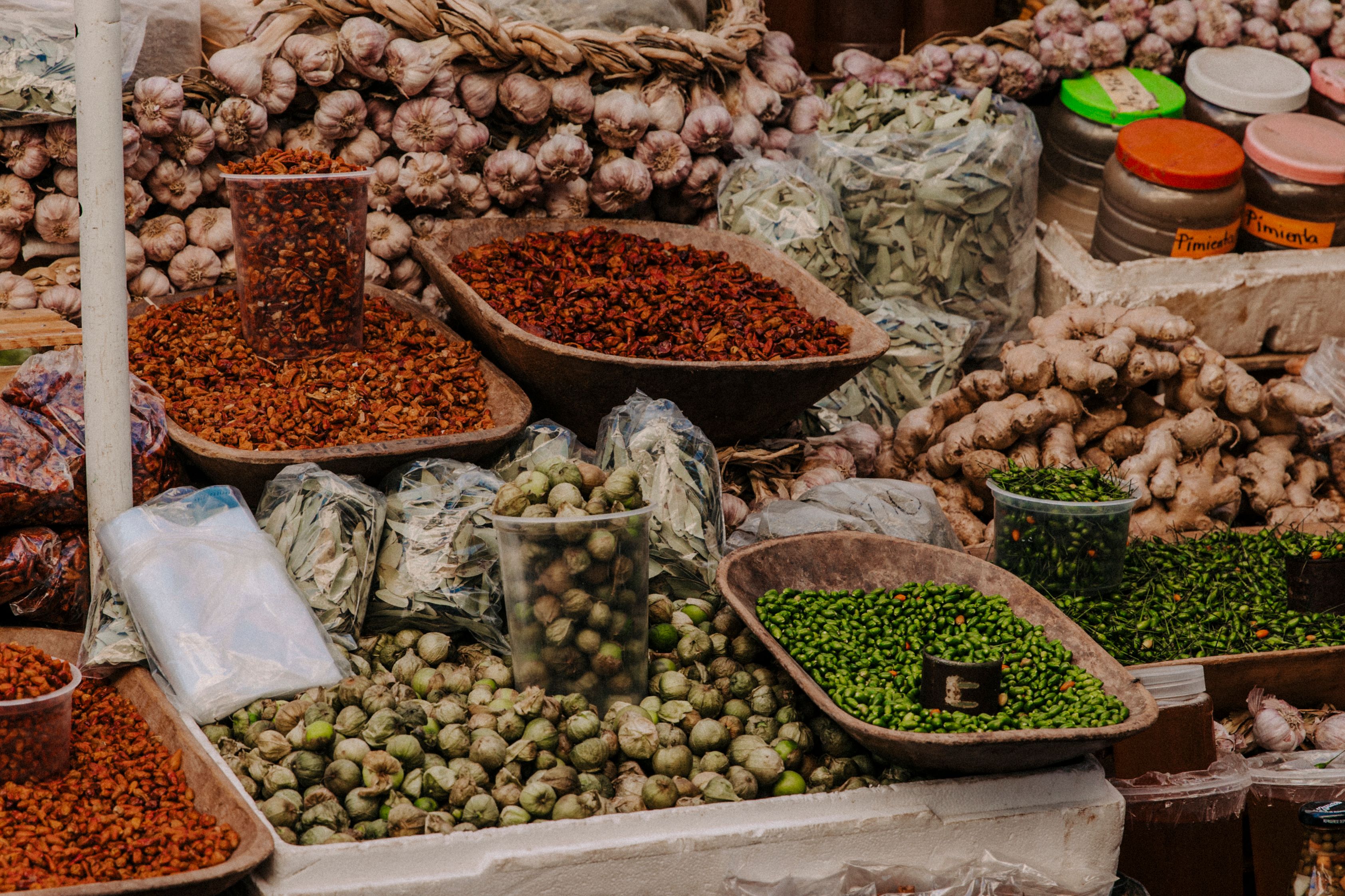 Free Vibrant display of fresh vegetables, spices, and herbs at a bustling outdoor market. Stock Photo