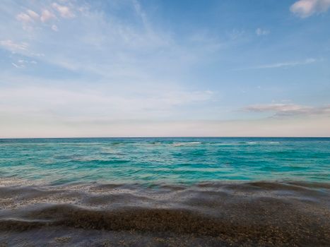 A peaceful tropical seascape with calm waves under a clear blue sky, capturing nature's serenity.