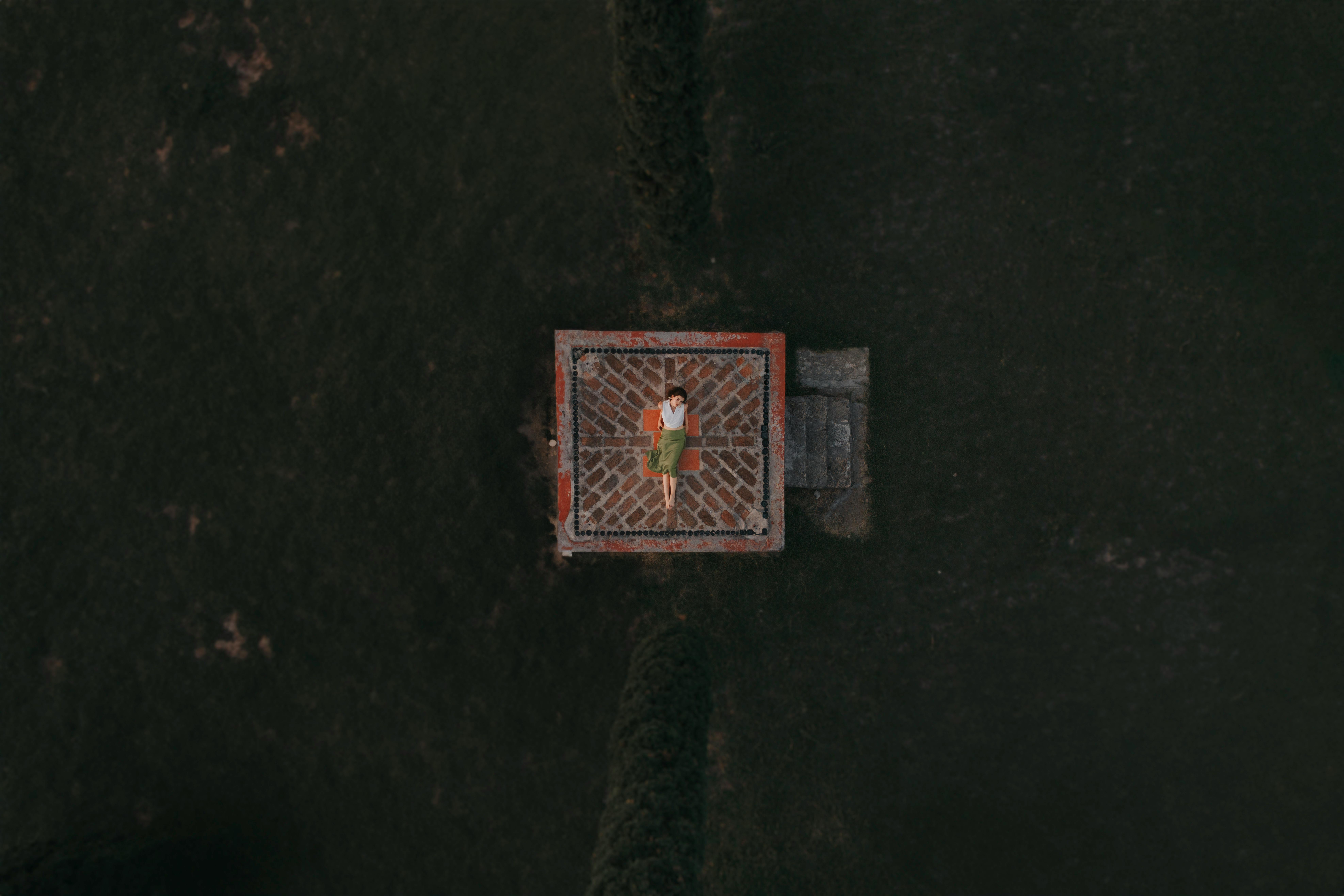 Free Aerial shot depicting a woman in a white shirt and green skirt standing on a platform. Stock Photo