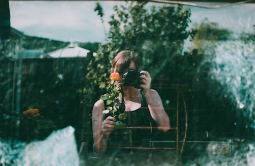 Woman Holding A Flower And Camera