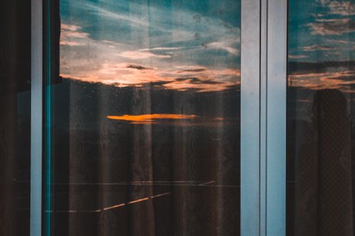 Free Reflective sunset captured through glass doors, showcasing a tranquil sky with vivid colors. Stock Photo