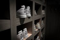 在灯光昏暗的房间里，标有“42”字样的白色运动鞋整齐地摆放在木制架子上