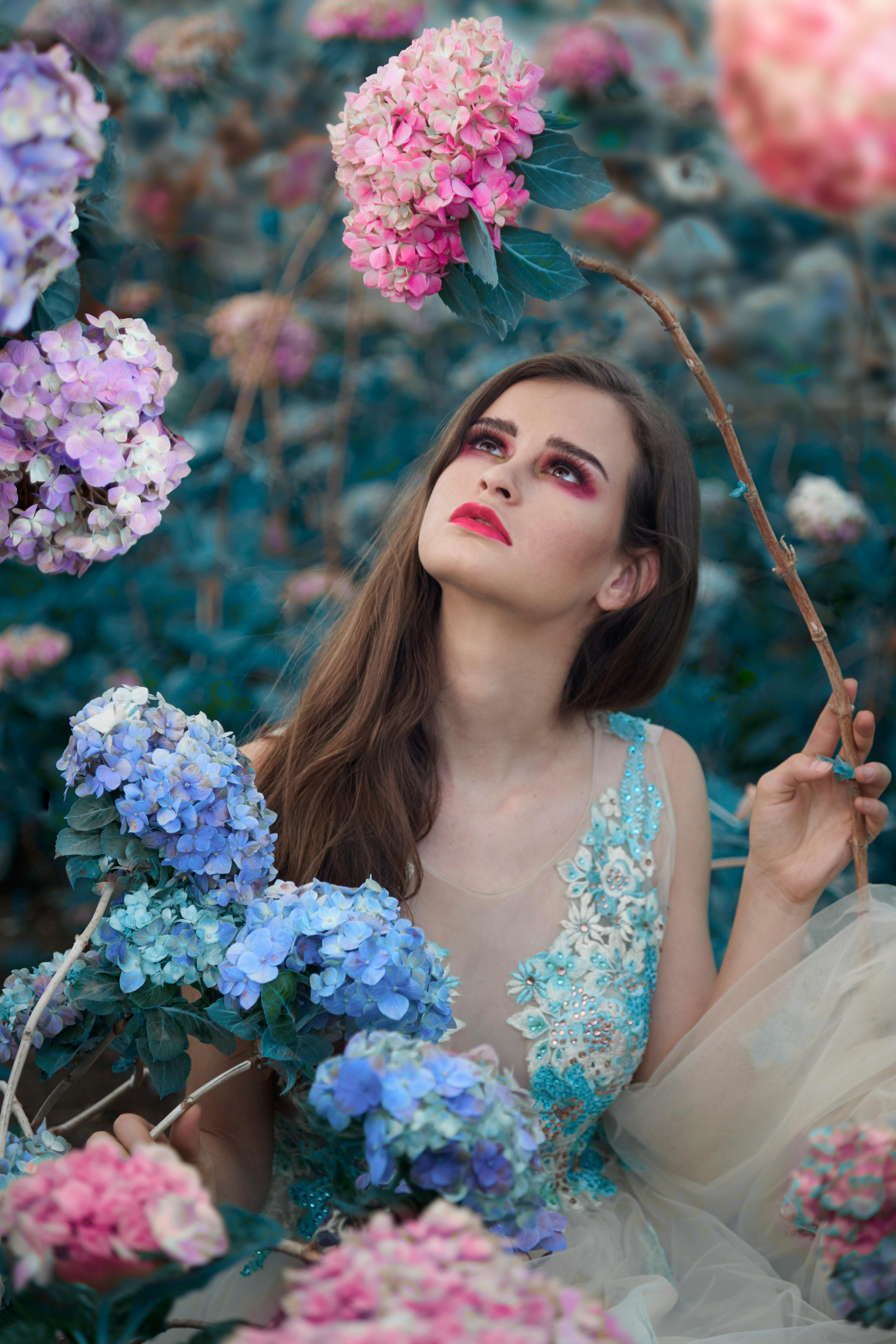 A captivating portrait of a woman in a floral garden surrounded by vibrant hydrangeas in full bloom.