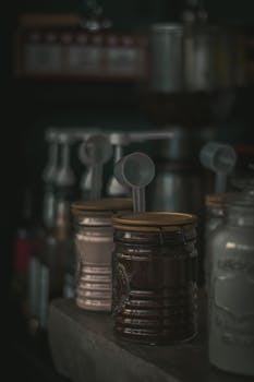 Moody close-up of coffee jars with measuring spoons on a cafe counter.