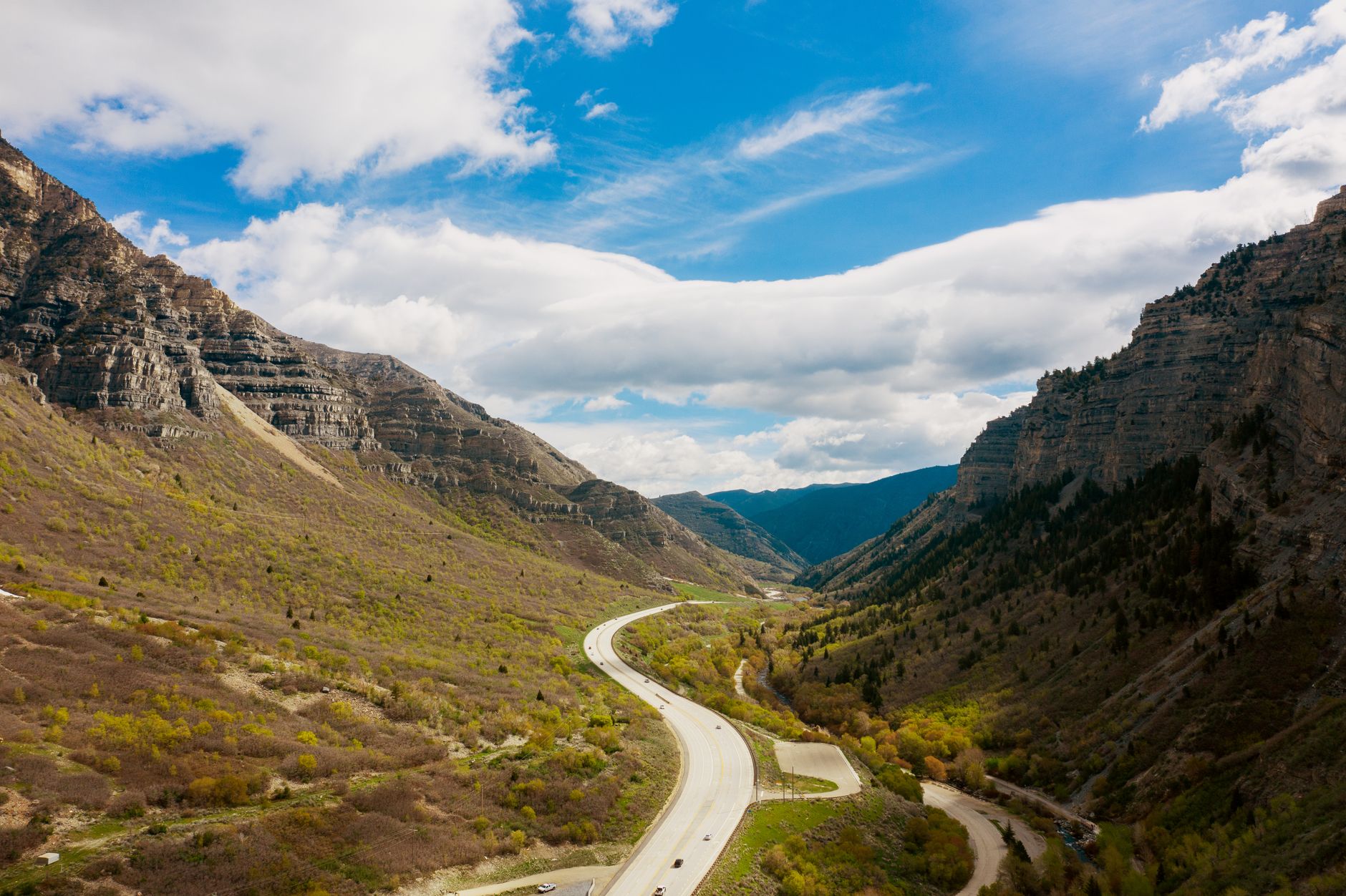 A breathtaking view of a highway winding through majestic Utah mountains under a vibrant blue sky.
