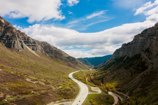 A breathtaking view of a highway winding through majestic Utah mountains under a vibrant blue sky.