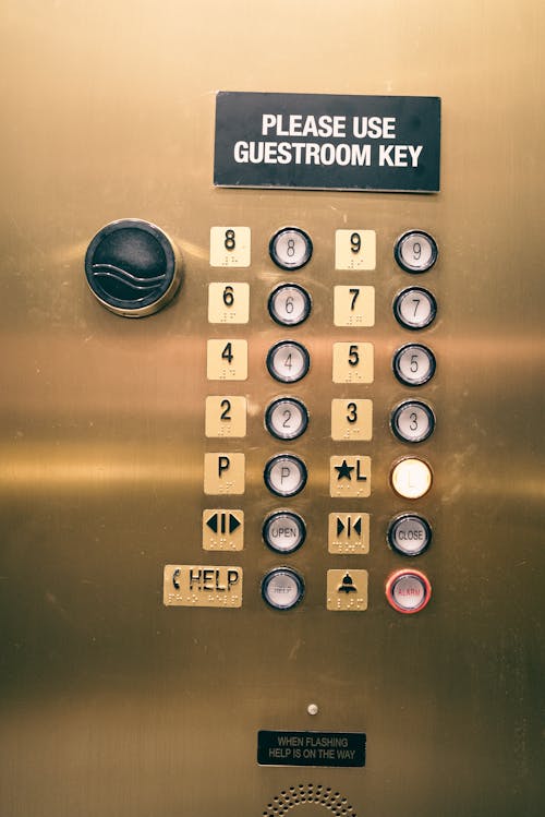 A gold elevator button with the words please use the guest key