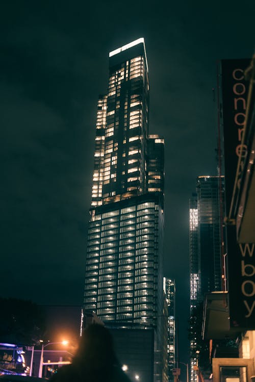 A person walking down the street at night in front of a tall building