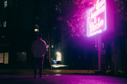 A man standing in front of a neon sign