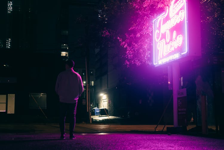 Man Standing Near Billboard At Night