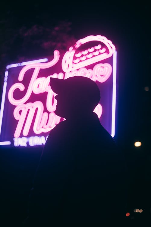 A man standing in front of a neon sign