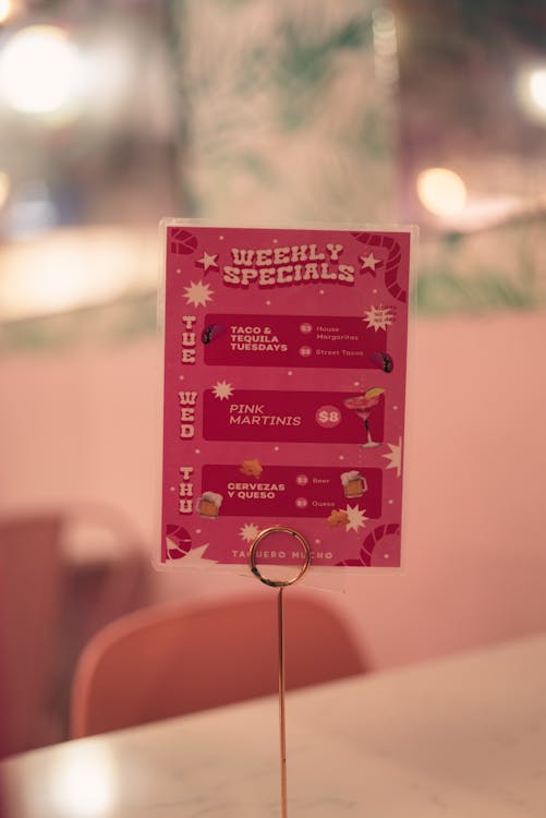 A menu on a table with a pink background