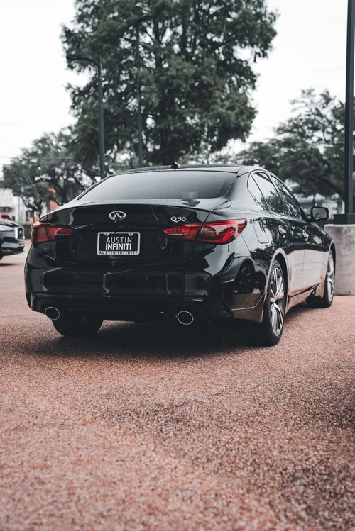 Free Rear view of a black Infiniti Q50 parked outdoors, showcasing modern design and elegance. Stock Photo
