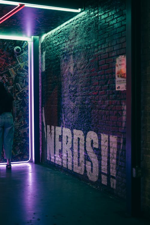 A person walking through a dark tunnel with neon lights