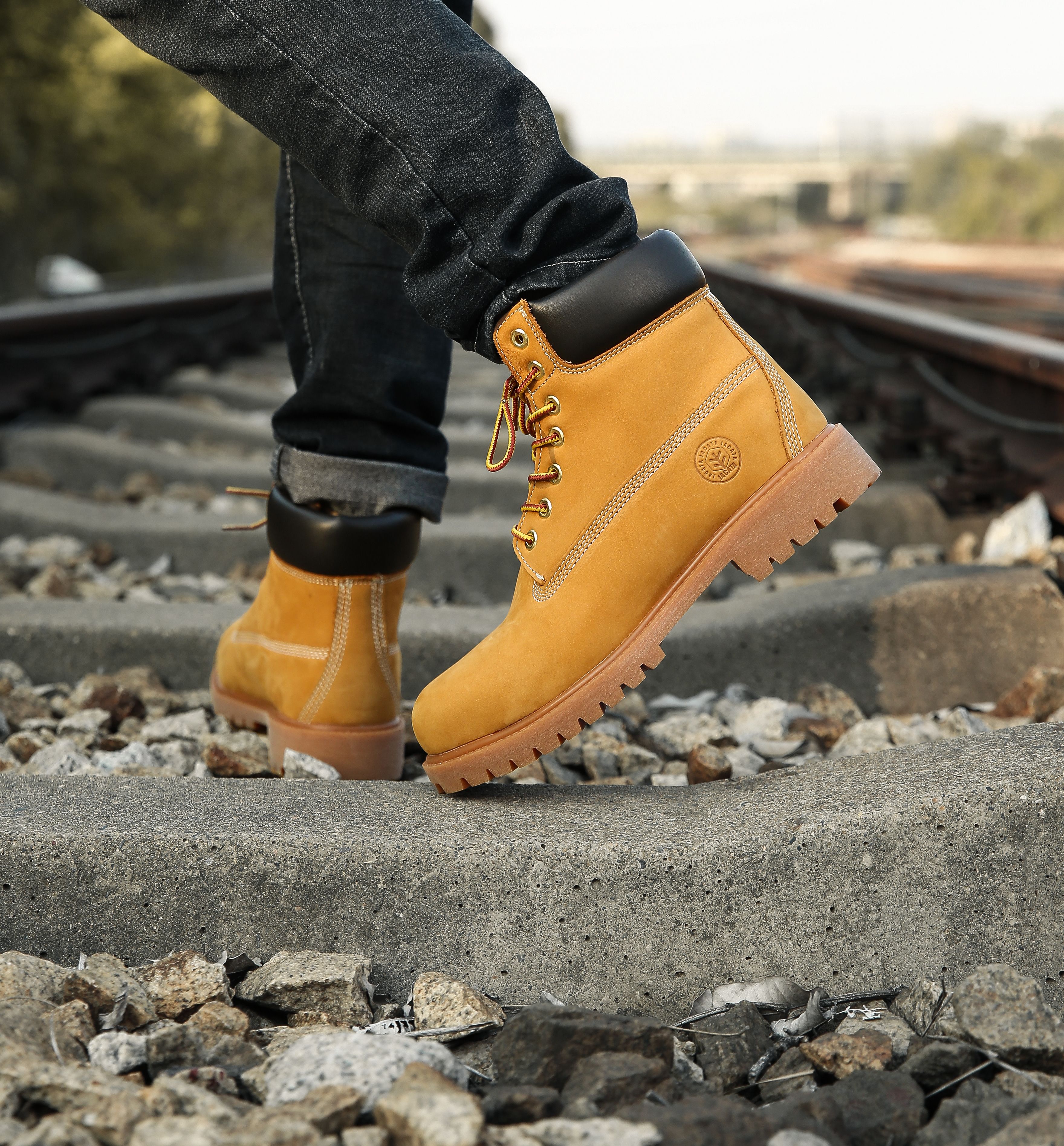 Close-up of yellow boots walking on railway tracks, showcasing adventure and style.
