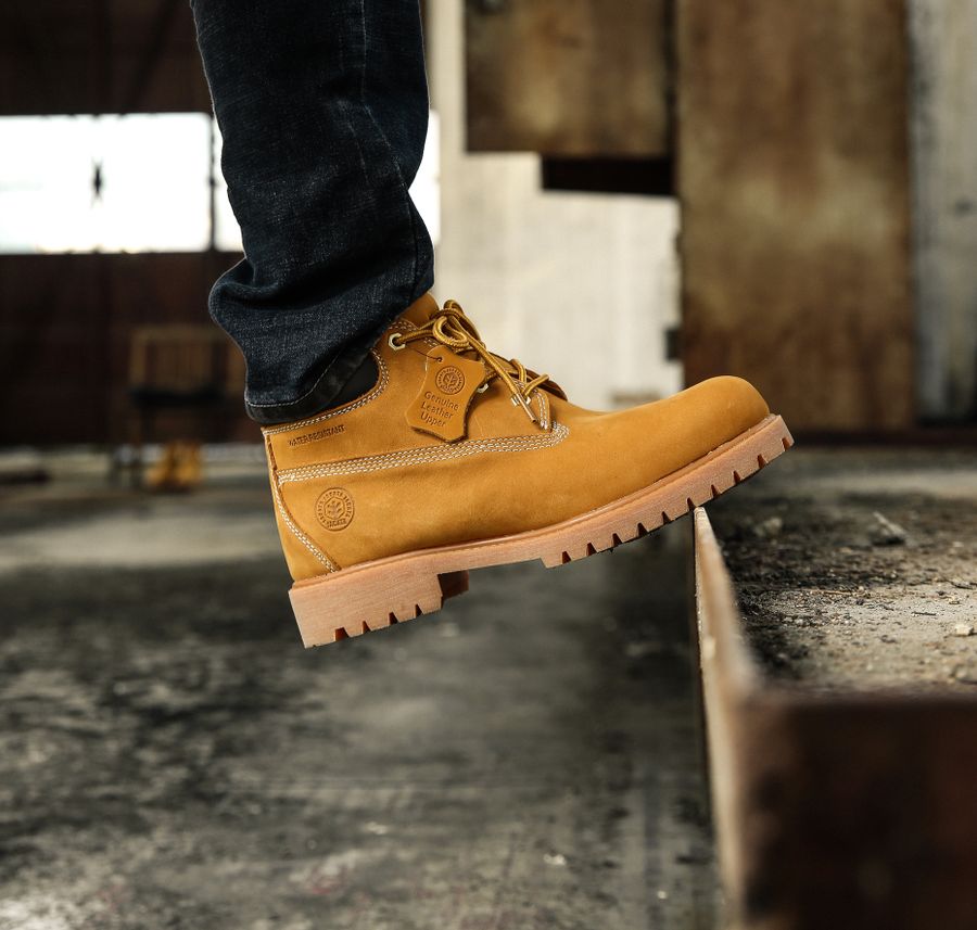 Heavy-duty work boot stepping onto a metal surface in an industrial environment