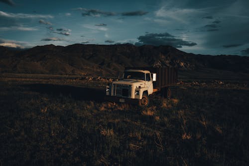 An old truck sits in the middle of a field