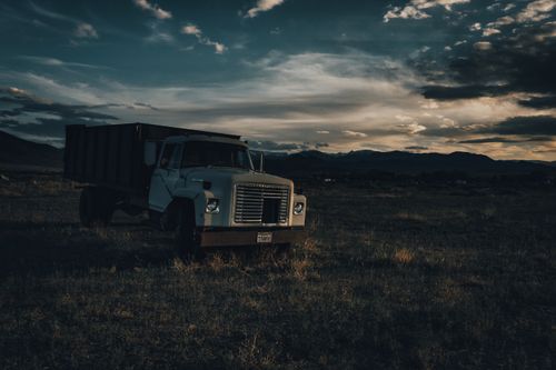 Free A parked vintage truck in a serene field during dusk in Monroe, Utah, with dramatic cloud formations Stock Photo