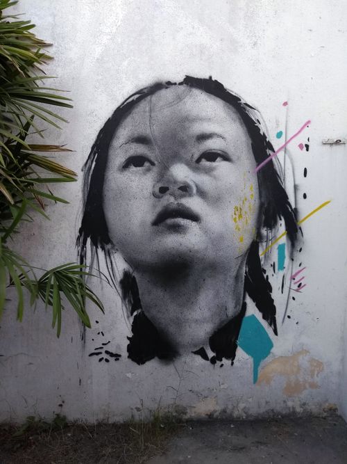 Free A striking street art portrait of a woman against a textured urban wall, featuring colorful accents. Stock Photo
