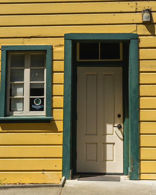 Charming yellow house with a wooden facade, green trim, and an inviting entrance.