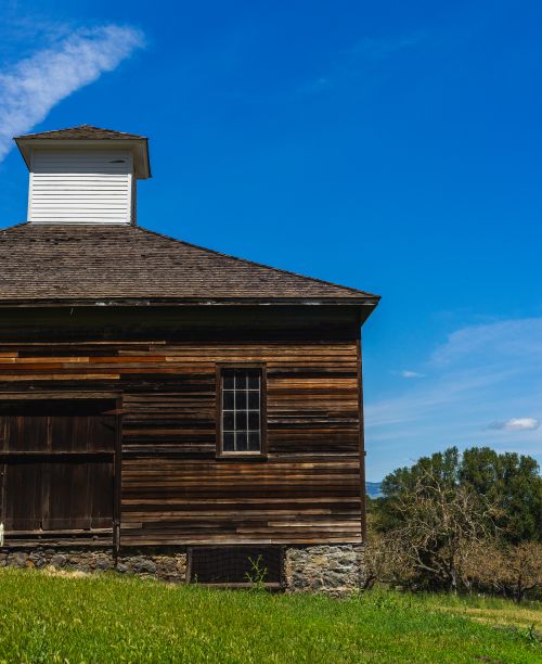 Free A rustic wooden cabin with a steep roof under a clear blue sky in a rural setting. Perfect for countryside themes. Stock Photo