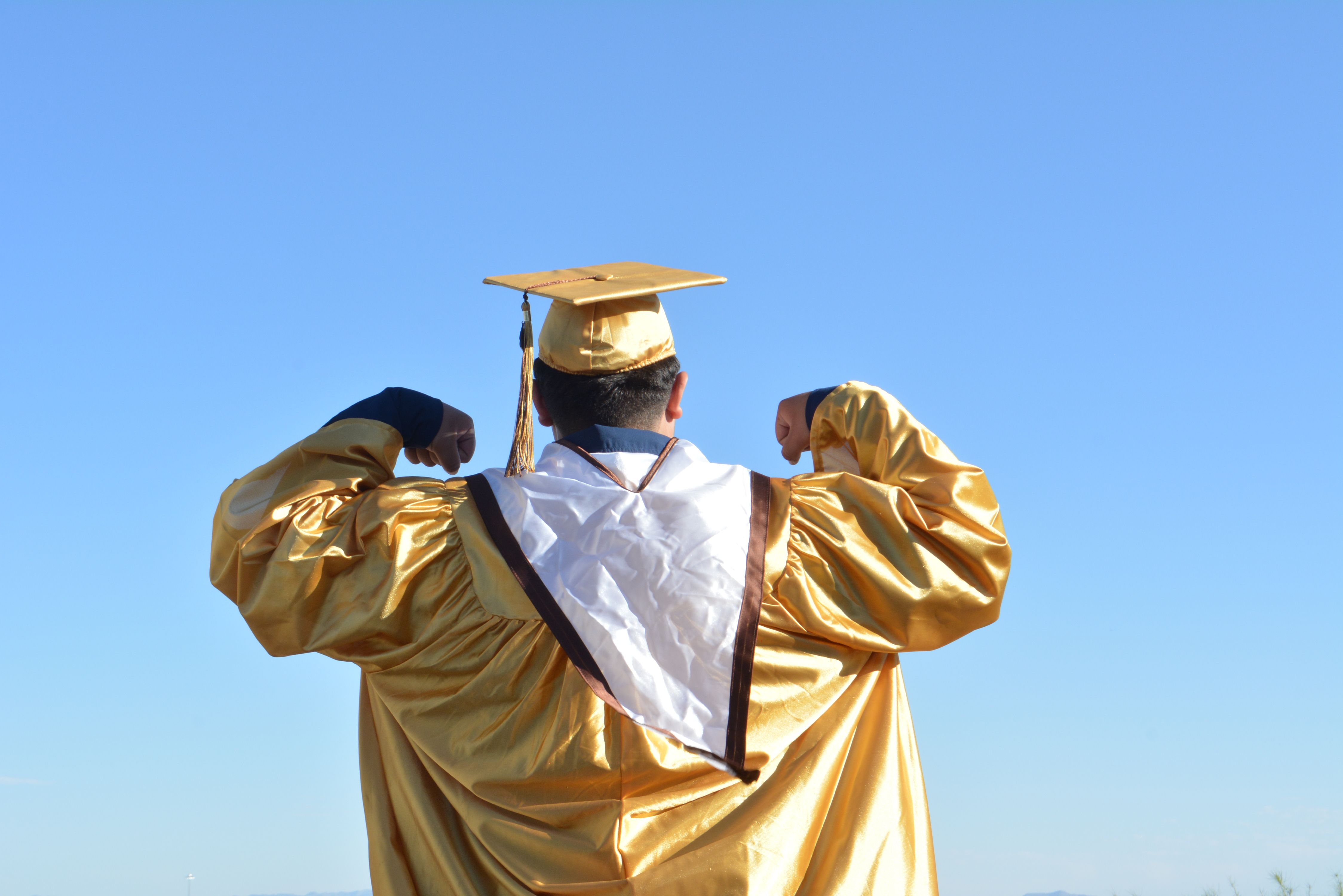 Man in Gold Graduation Gown Standing against Blue Sky  Free Stock Photo