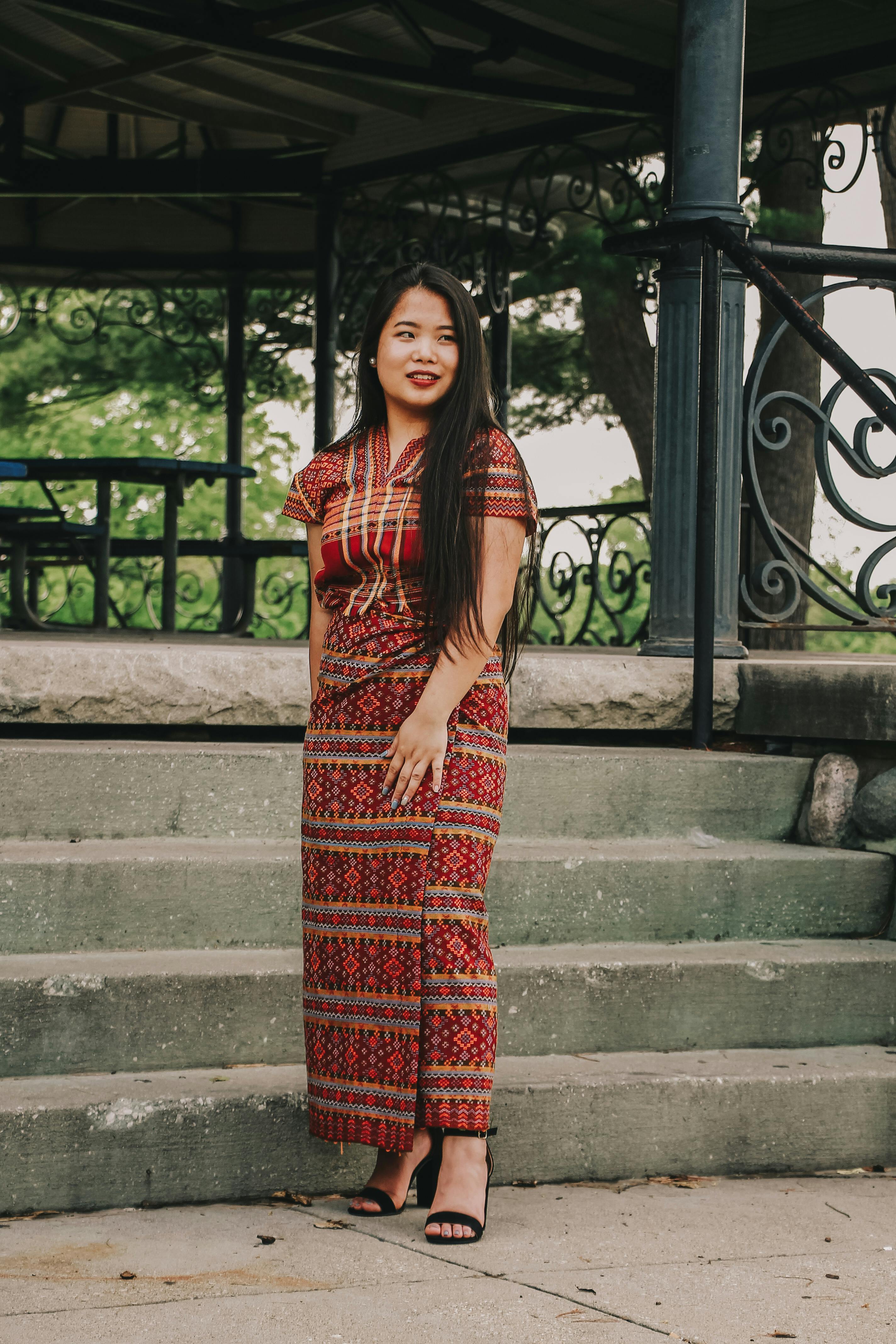 一名妇女在户外凉亭旁优雅地展示着有图案的传统服装
