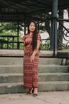 一名妇女在户外凉亭旁优雅地展示着有图案的传统服装