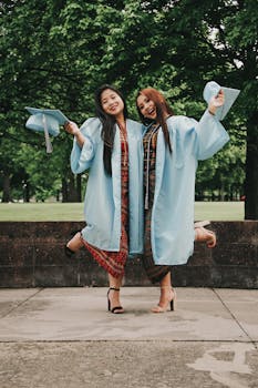 两名妇女头戴礼帽、身着礼服，在户外庆祝毕业，表达着幸福之情