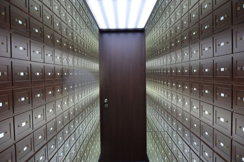 Free Wooden lockboxes line the walls of a modern, secure vault with a central wooden door. Stock Photo