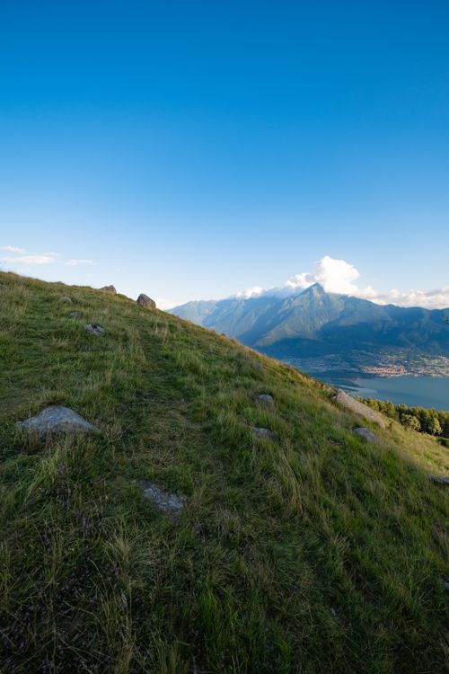 Free Serene mountain slope overlooking a lake under a clear blue sky. Stock Photo