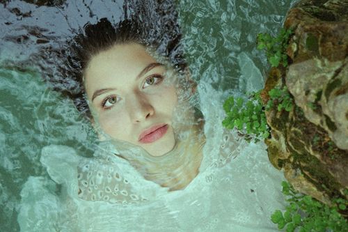 Free A mesmerizing portrait of a woman partially submerged in tranquil water, combining nature and beauty. Stock Photo