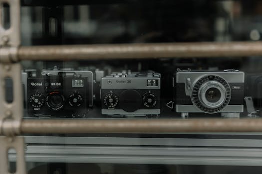 Showcase of vintage cameras behind a storefront window, emphasizing classic technology.
