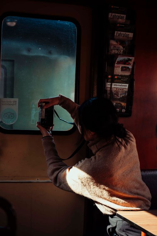 Free Woman photographing through a train window in Oybin, Germany, highlighting travel and discovery. Stock Photo