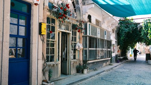 Free Picturesque alley with rustic architecture, open door, vibrant flowers, and vintage charm. Stock Photo