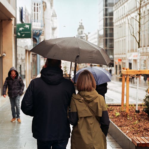 A couple walking down a sidewalk with an umbrella