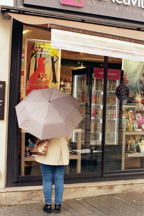A woman with an umbrella standing in front of a store