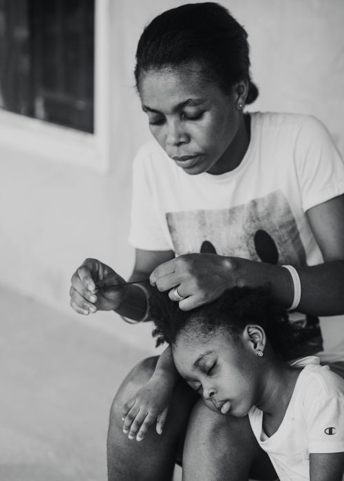 Free A mother lovingly braids her daughter's hair in this intimate black and white portrait. Stock Photo