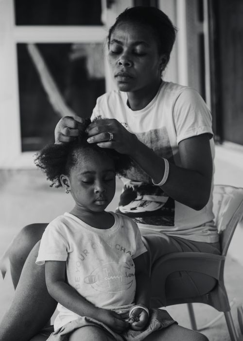 Free A loving mother gently braids her daughter's hair in a close-up black and white portrait. Stock Photo