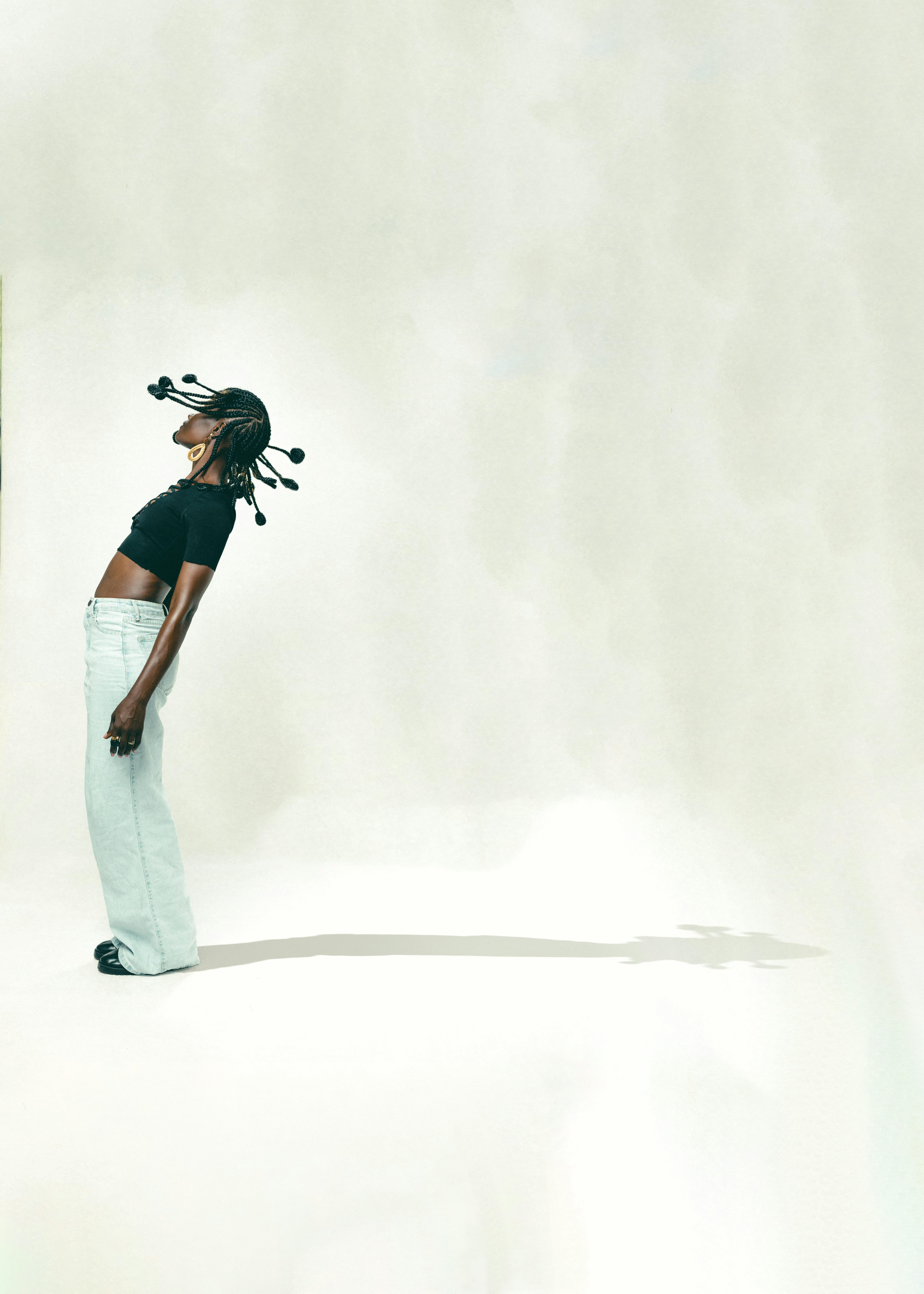 Young woman with braided hair leaning backwards in a studio shot.