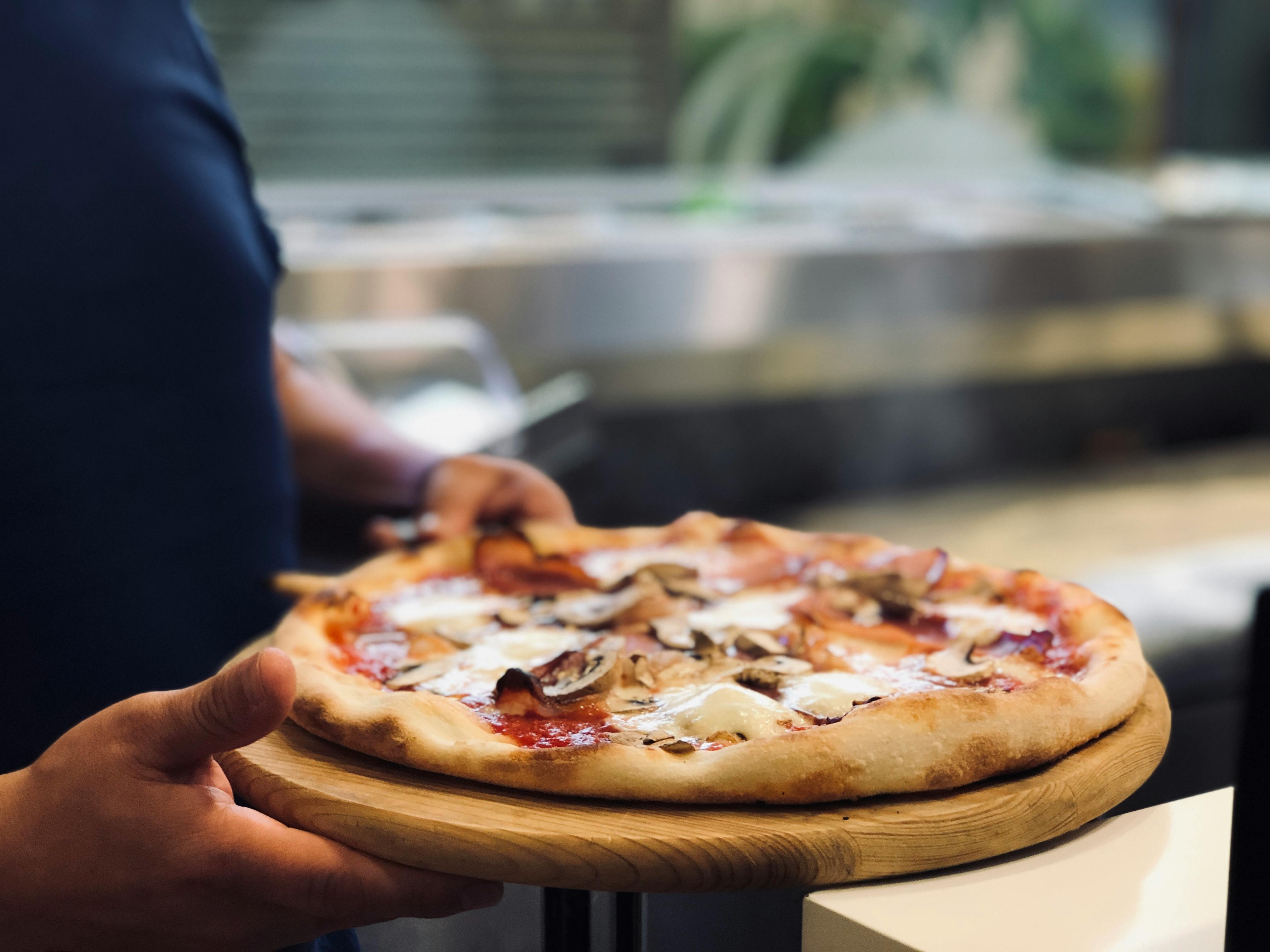 person holding whole pan of baked pizza