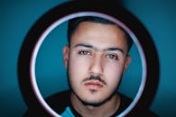 一张用环形灯框起来的年轻人特写肖像，他留着胡须，看起来像现代摄影作品